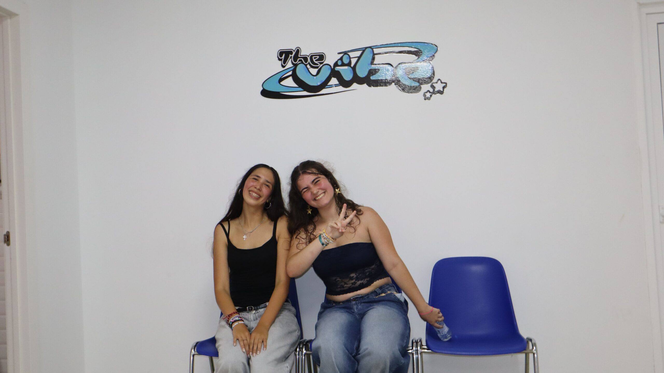 Dos alumnas sonriendo bajo el logo de The Vibe