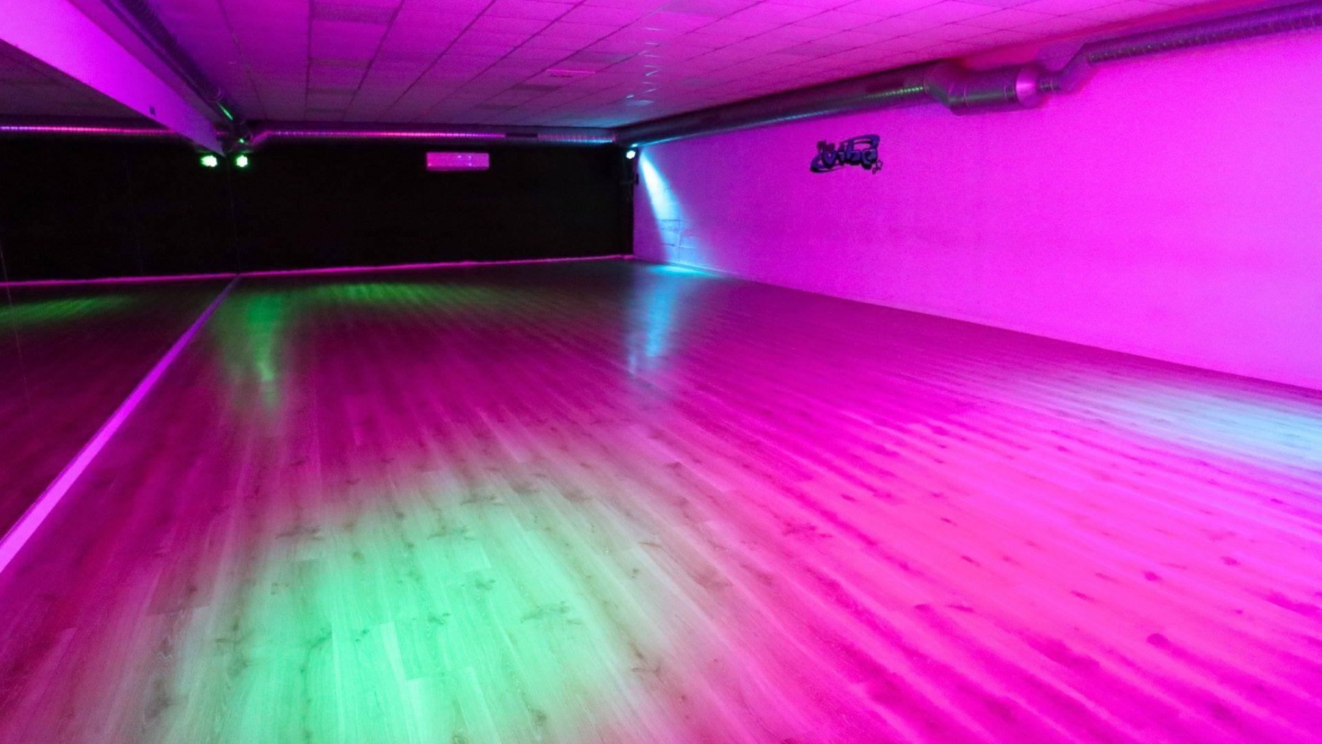 Aula iluminada con luces rosas y verdes, preparada para un show